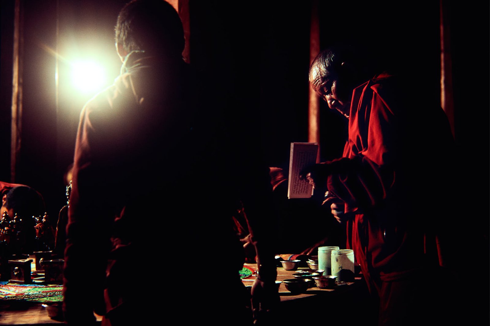 monk reading in front of a sand mandala